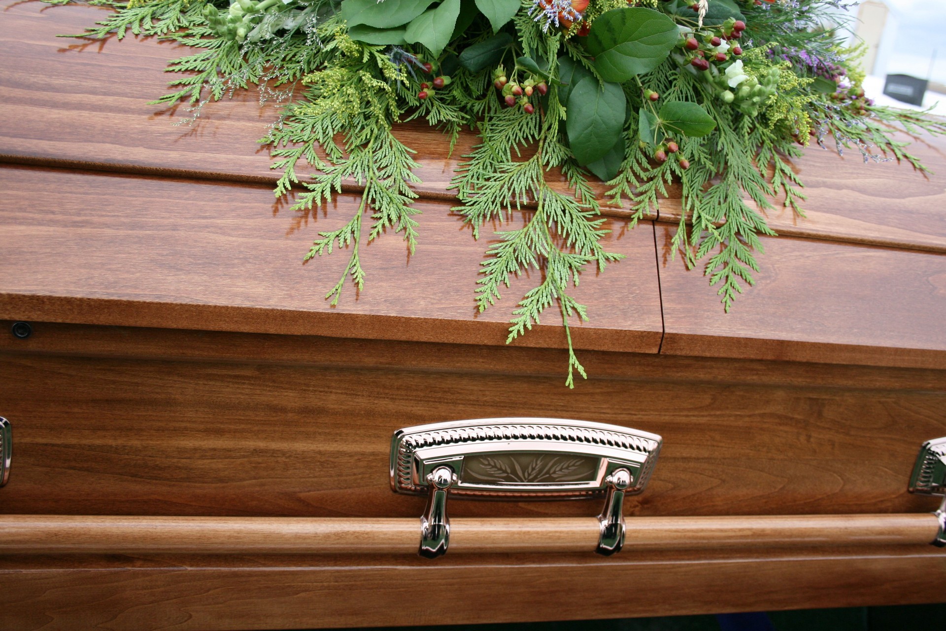 Beautiful closed wooden coffin with plant arrangement on top